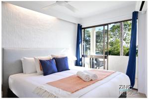 ヌーサヘッズにあるSt Tropez 10 - Relaxing Noosa Water Views & Poolの大きな白いベッドと青い枕のある寝室