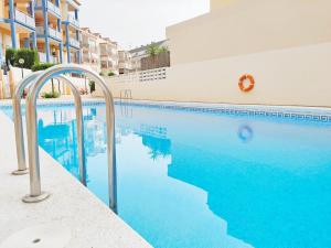 a swimming pool with blue water in front of a building at Global Properties, Apartamento con piscina y terraza en Canet playa in Canet de Berenguer
