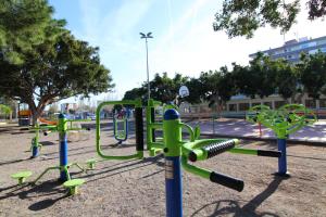 a playground with green equipment in a park at Global Properties, Apartamento con piscina y terraza en Canet playa in Canet de Berenguer