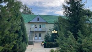 a house with a green roof and some trees at PARK HOTEL Uralsk in Uralsk