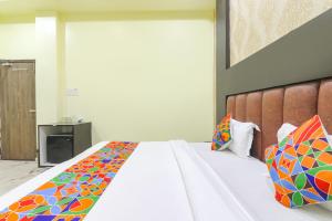 a bedroom with a large white bed with colorful pillows at FabExpress GS Residency in Varanasi