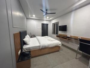 Schlafzimmer mit einem Bett und einem Flachbild-TV in der Unterkunft KKM Highlands in Kurnool