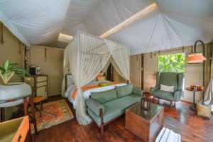 a bedroom with a bed and a couch and a chair at Kanva Ubud in Tegalalang