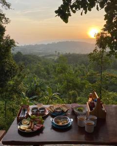 Ban Phu Hiにあるภูคำฮ้อมคลิฟฟ์ลอดจ์ แอนด์ โฮมสเตย์ Phu come home cliff Lodge & Homestayの夕日を背景に食べ物を置いたテーブル