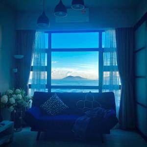 - un salon avec un canapé bleu en face d'une fenêtre dans l'établissement Mango House2-SeaView,Wifi,Swimmingpool,Gym-JQ, à Kota Kinabalu