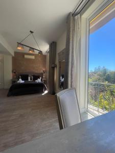 a bedroom with a bed and a large window at Hôtel de La Fossette in Le Lavandou