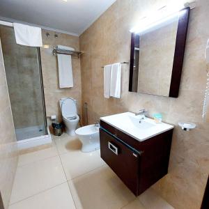 y baño con aseo, lavabo y ducha. en Hotel Embaixador en Beira
