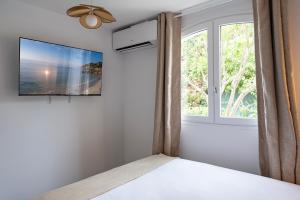 een slaapkamer met een raam en een tv aan de muur bij Superbe 3 pièces dans Saint Tropez avec piscine et terrasse in Saint-Tropez