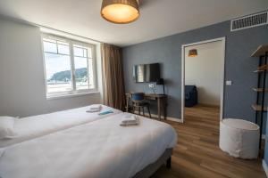 a hotel room with a large bed and a desk at Hôtel de la Baie in Crozon