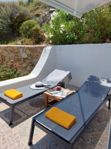 patio z 2 krzesłami, stołem i ławką w obiekcie Apollon Village Hotel w mieście Anafi