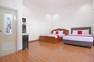 um quarto com 2 camas e piso em madeira em RedDoorz near UMY Yogyakarta em Yogyakarta