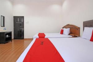 um quarto de hotel com duas camas com um cobertor vermelho em RedDoorz near UMY Yogyakarta em Yogyakarta