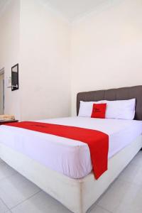 a large white bed with a red blanket on it at RedDoorz near UMY Yogyakarta in Yogyakarta
