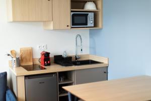a small kitchen with a sink and a microwave at Hôtel de la Baie in Crozon