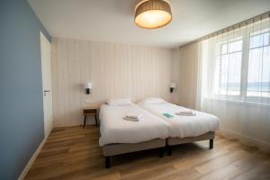 a bedroom with a white bed in a room with a window at Hôtel de la Baie in Crozon