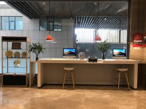 a lobby with a desk with two stools and two monitors at Holiday Inn Express Shijiazhuang High-tech Zone, an IHG Hotel in Shijiazhuang
