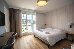 a hotel room with a bed and a large window at Hôtel de la Baie in Crozon