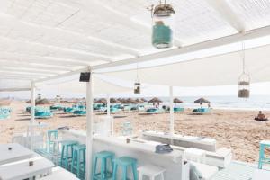 a beach with white tables and blue chairs and the ocean at Valencia Ático playa Patacona. Parking incluido in Valencia