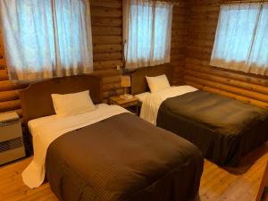 a bedroom with two beds in a log cabin at Awone Shirakami Juniko in Fukaura
