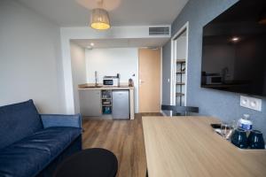 a living room with a couch and a table and a kitchen at Hôtel de la Baie in Crozon
