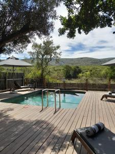 a swimming pool on a wooden deck with an umbrella at Barefoot Addo Elephant Lodge in Addo