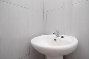 a white sink in a white tiled bathroom at RedDoorz near UMY Yogyakarta in Yogyakarta +47 photos