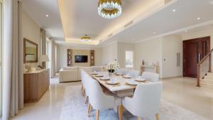 a dining room with a table and white chairs at Primestay - Flame Tree Ridge 4BR Villa with Private Pool in Dubai