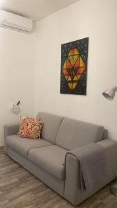 a couch in a living room with a painting on the wall at Bilocale Carrara Centro con giardino e parcheggio moto in Carrara