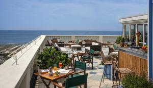 uma varanda com mesas e cadeiras e o oceano em Palace Hotel em Viareggio