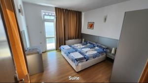 a bedroom with a bed with a blue comforter and a window at Nushev Hotel in Sveti Vlas +59 photos