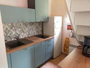 uma cozinha com armários azuis, um lavatório e um frigorífico em Le Pech de Sireuil em Groléjac