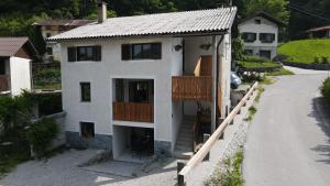 a white house with a balcony and a road at Apartma Ten Sen in Kobarid