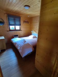 um quarto com uma cama num chalé de madeira em Le Mont Céleste em Nonceveux