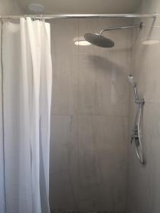 a shower with a white shower curtain in a bathroom at Apartamenty Elbląska 20A in Braniewo