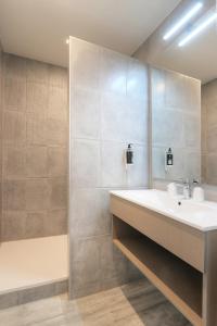 a bathroom with a white sink and a tub at Hôtel La Petite Sirène Quiberon in Quiberon