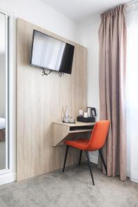 a room with a desk with a television on the wall at Hôtel La Petite Sirène Quiberon in Quiberon