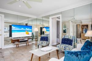 uma sala de estar com uma televisão grande e cadeiras azuis em San Marco Gulf Beach Views 3rd Floor em Venice