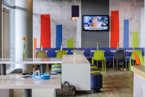 a room with tables and chairs and a tv on a wall at ibis budget Nürnberg City Messe in Nürnberg