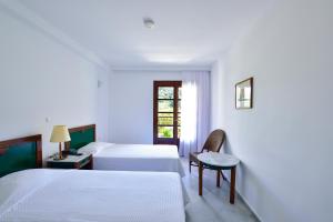 a hotel room with two beds and a window at Kalidon beach Hotel in Kokkari