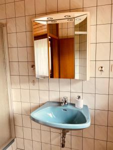ein Badezimmer mit einem blauen Waschbecken und einem Spiegel in der Unterkunft Appartements D'Angelo in Bodensdorf