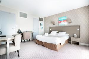 a hotel room with a bed and a desk and a table at Hôtel La Petite Sirène Quiberon in Quiberon