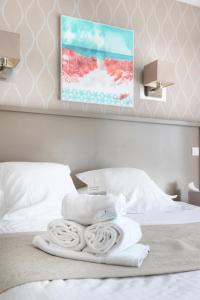 a bed with a pile of towels on top of it at Hôtel La Petite Sirène Quiberon in Quiberon
