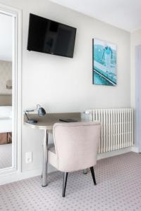 a desk with a chair and a television on a wall at Hôtel La Petite Sirène Quiberon in Quiberon