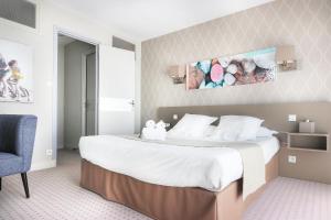 a bedroom with a large bed and a chair at Hôtel La Petite Sirène Quiberon in Quiberon