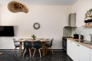 una cocina con mesa y sillas y un reloj en la pared en ALS Holiday Houses by Konnect, 900m from Ipsos Beach en Ypsos