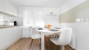a white kitchen with a white table and chairs at PerfectSpa Apartment in Humenné
