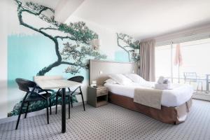 1 dormitorio con cama, escritorio y un mural de árboles en La Petite Sirène, en Quiberon