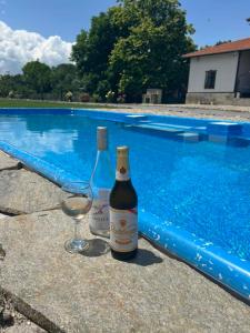two bottles of wine and a glass next to a swimming pool at Къща за гости Мелницата in Elhovo