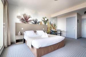 a hotel room with a large bed with white sheets at Hôtel La Petite Sirène Quiberon in Quiberon