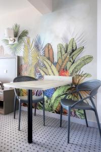 a table and two chairs in front of a mural of plants at Hôtel La Petite Sirène Quiberon in Quiberon